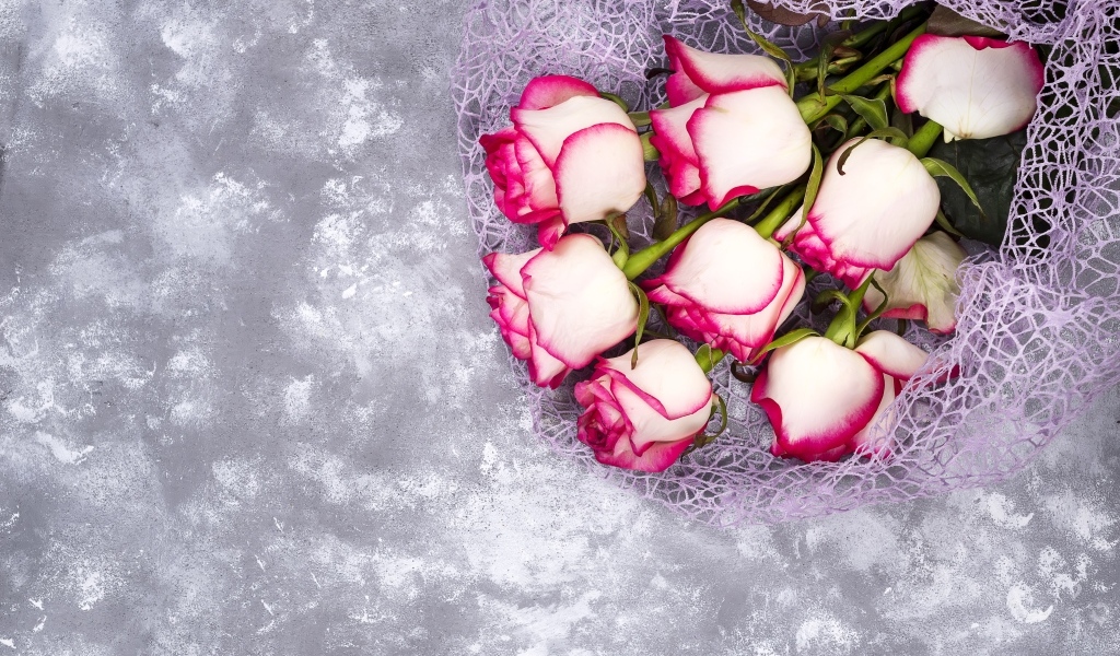 Красивый букет роз в упаковке на сером столе