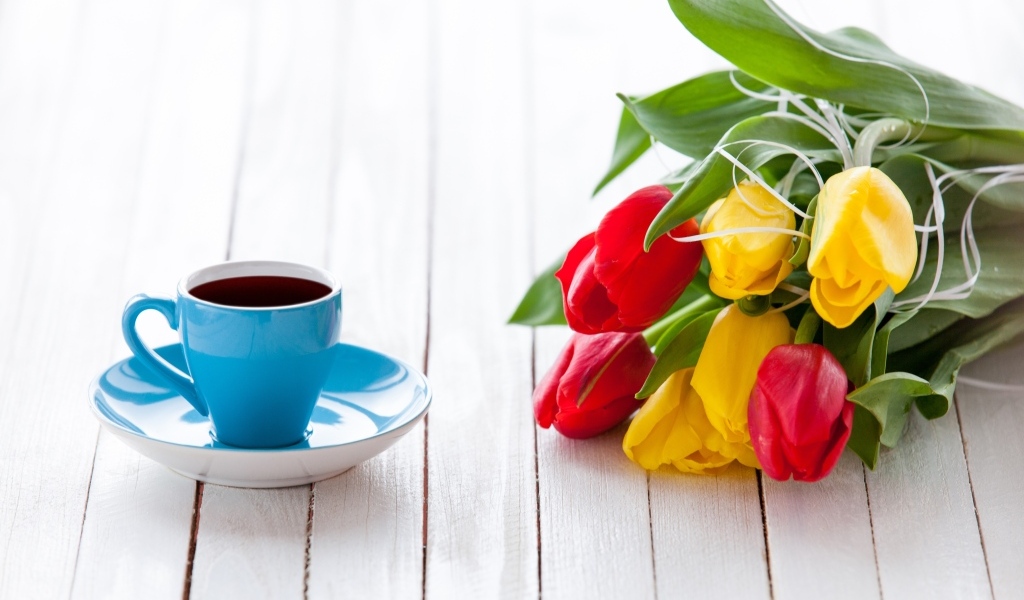 Голубая чашка на столе с букетом тюльпанов