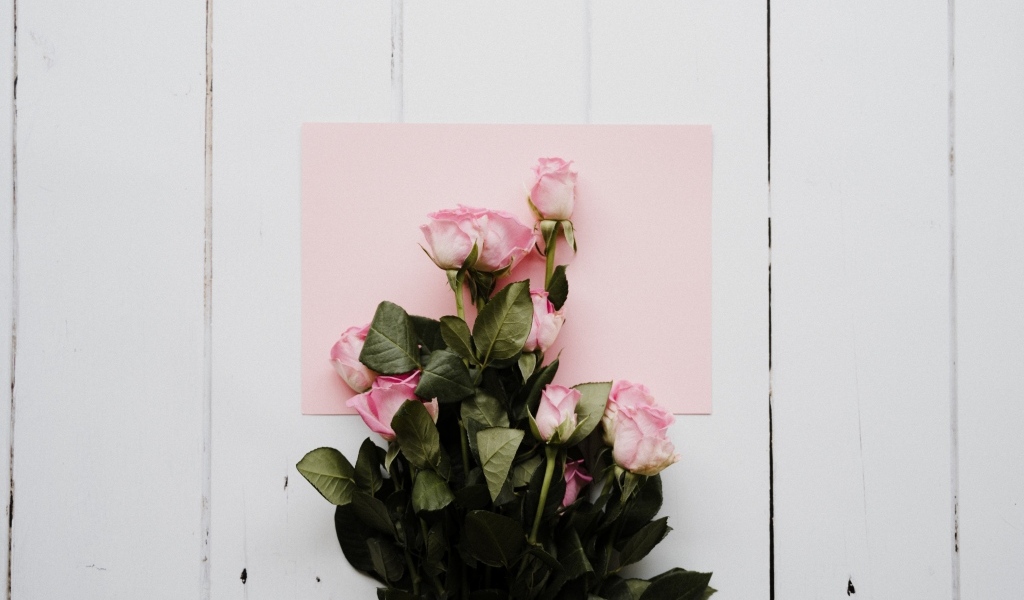 Букет роз с розовым листом бумаги на столе