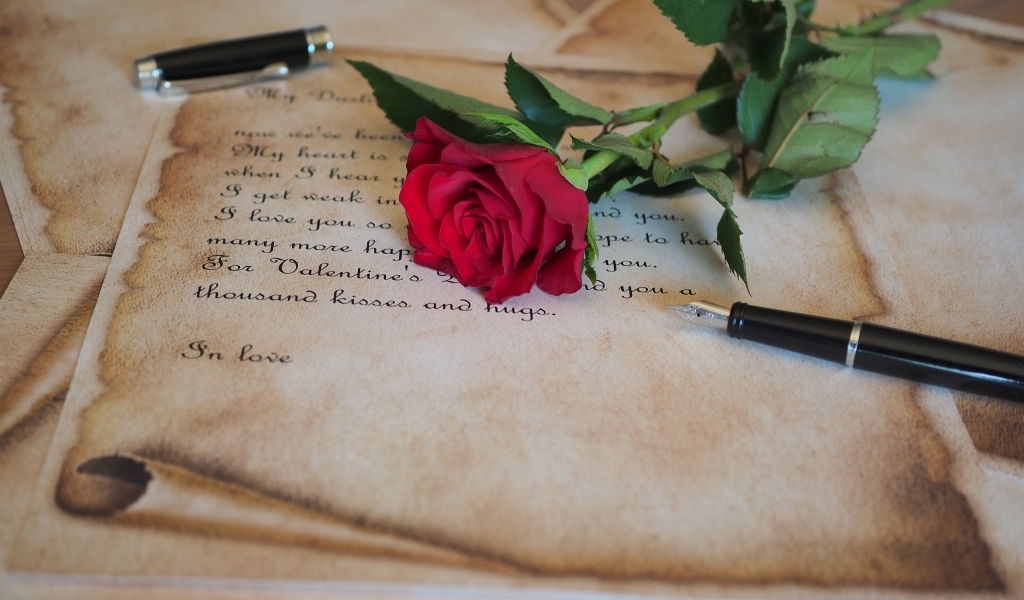 Красная роза с запиской и ручкой на столе