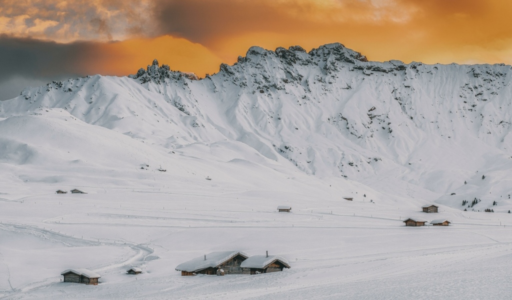 Красивая заснеженная гора под оранжевым небом