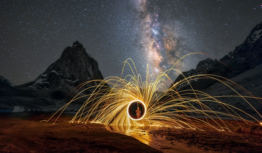 Огненное шоу под ночным красивым небом в горах