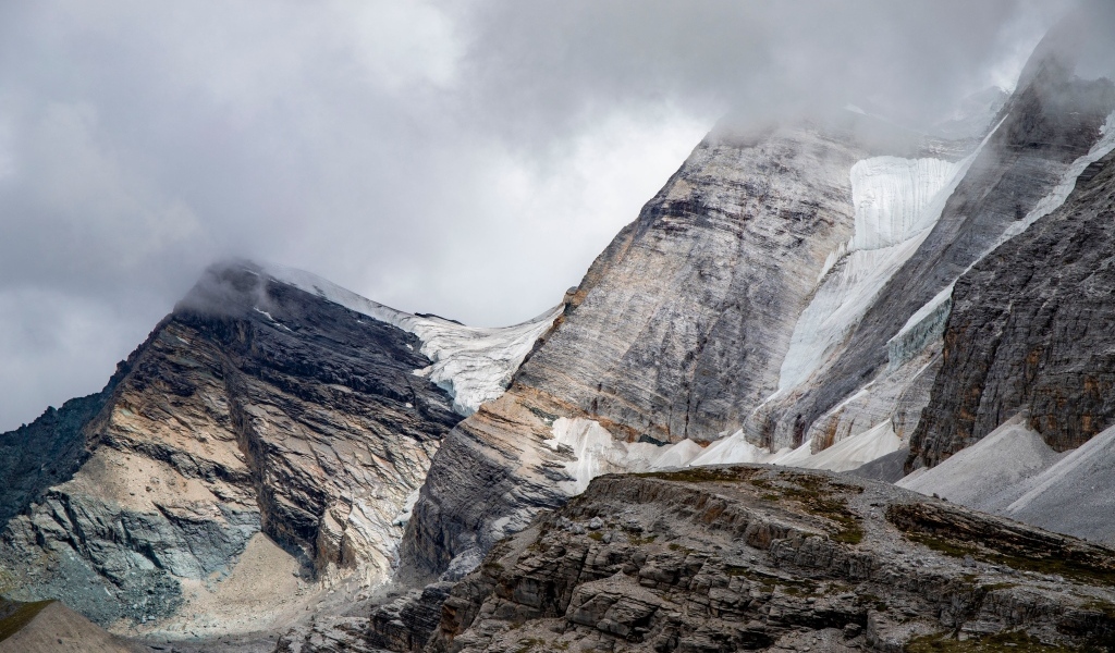 Высокие каменные горы в белых облаках