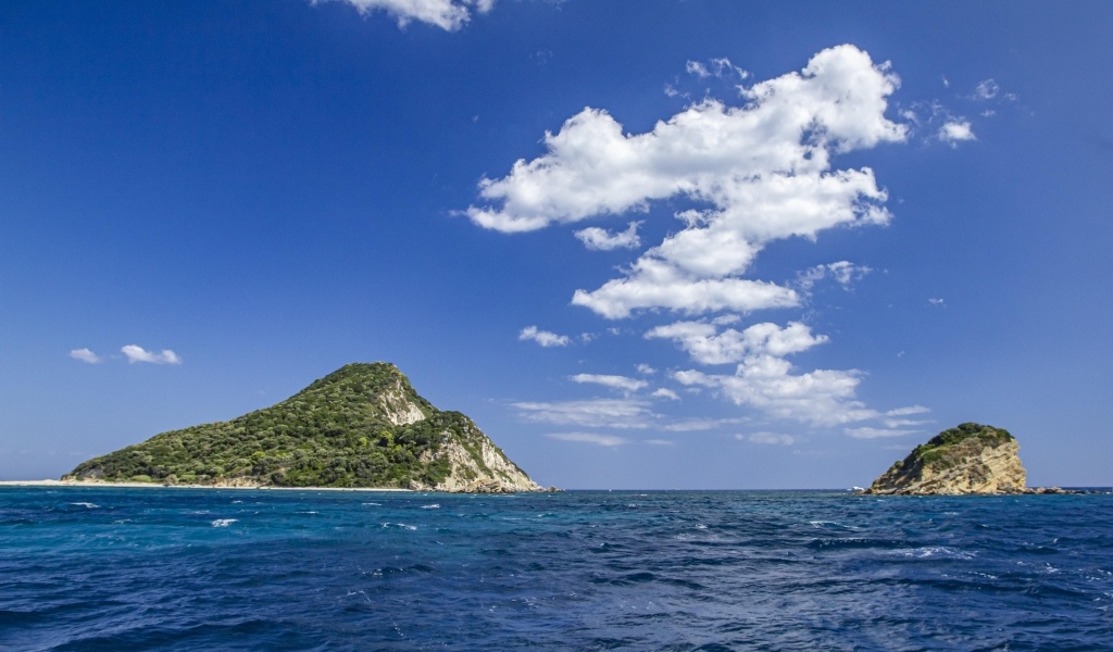 Покрытые зеленью горы в море под голубым небом