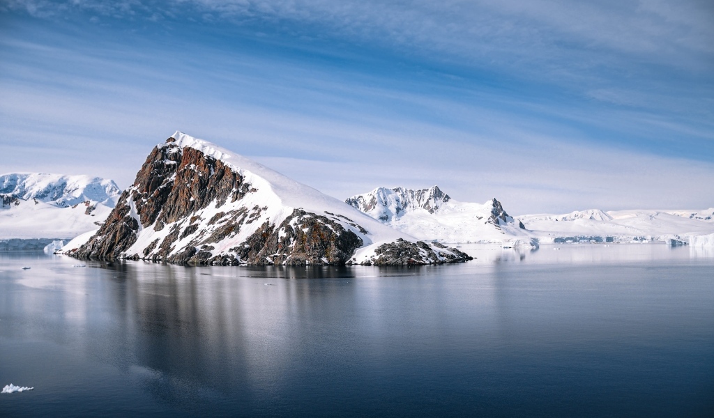 Заснеженная гора на берегу моря под голубым  небом