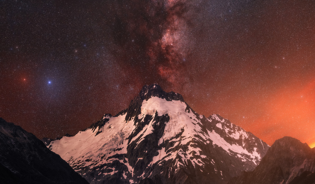 Заснеженная вершина горы под звездным небом