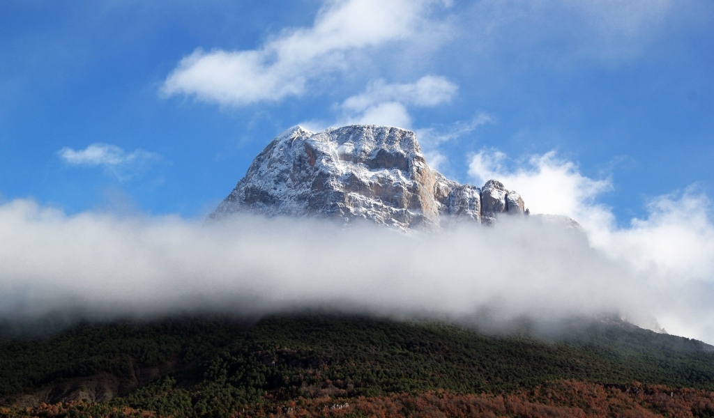 Заснеженная горная вершина в белых облаках