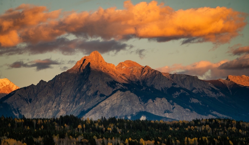 Солнце в облаках освещает вершину горы