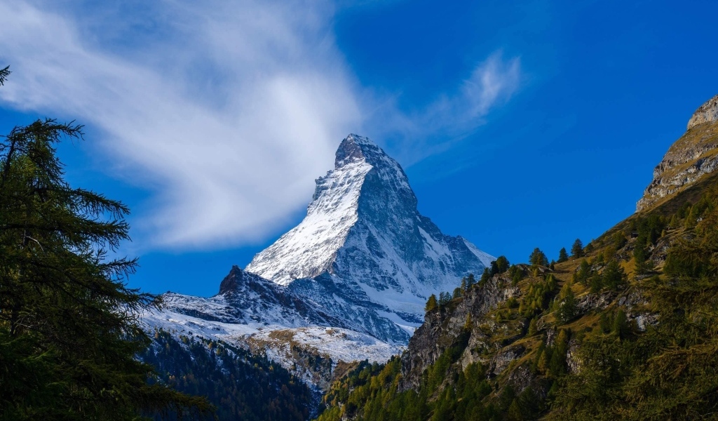 Вид на высокую заснеженную гору под голубым небом