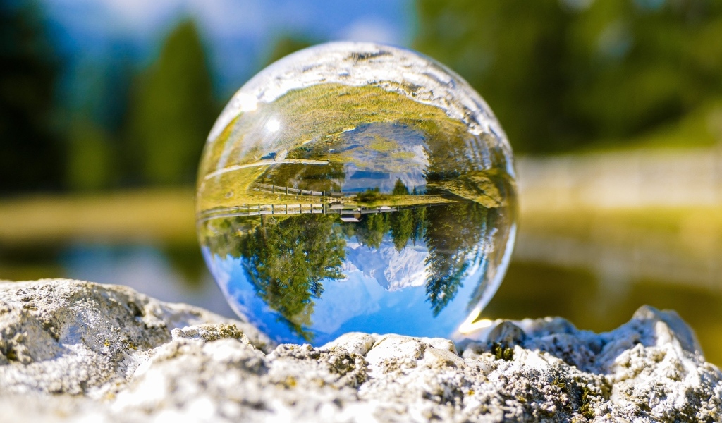 Стеклянный шар стоит на камне у воды