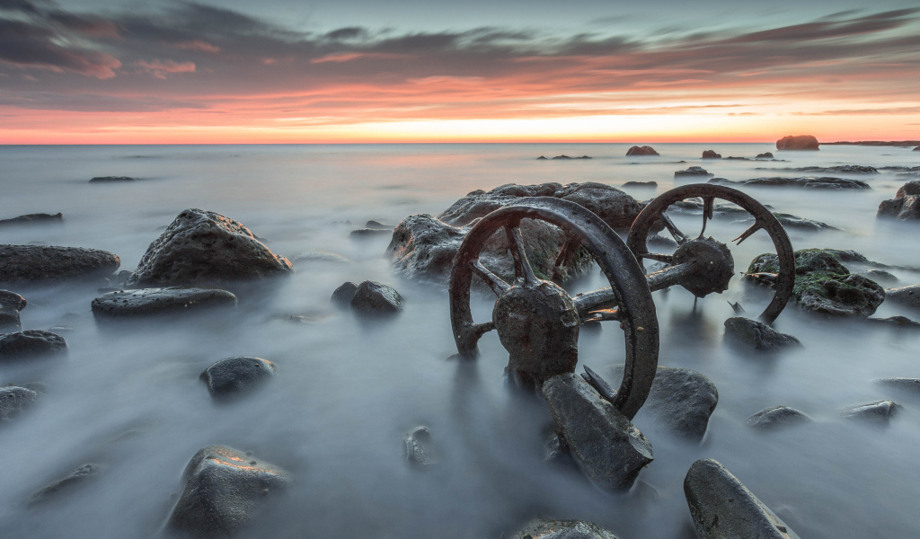 Старые колеса лежат в воде с камнями