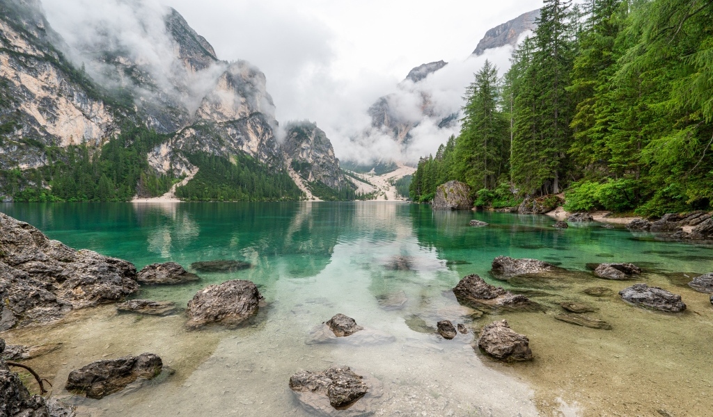 Камни лежат в воде озера в холодных горах