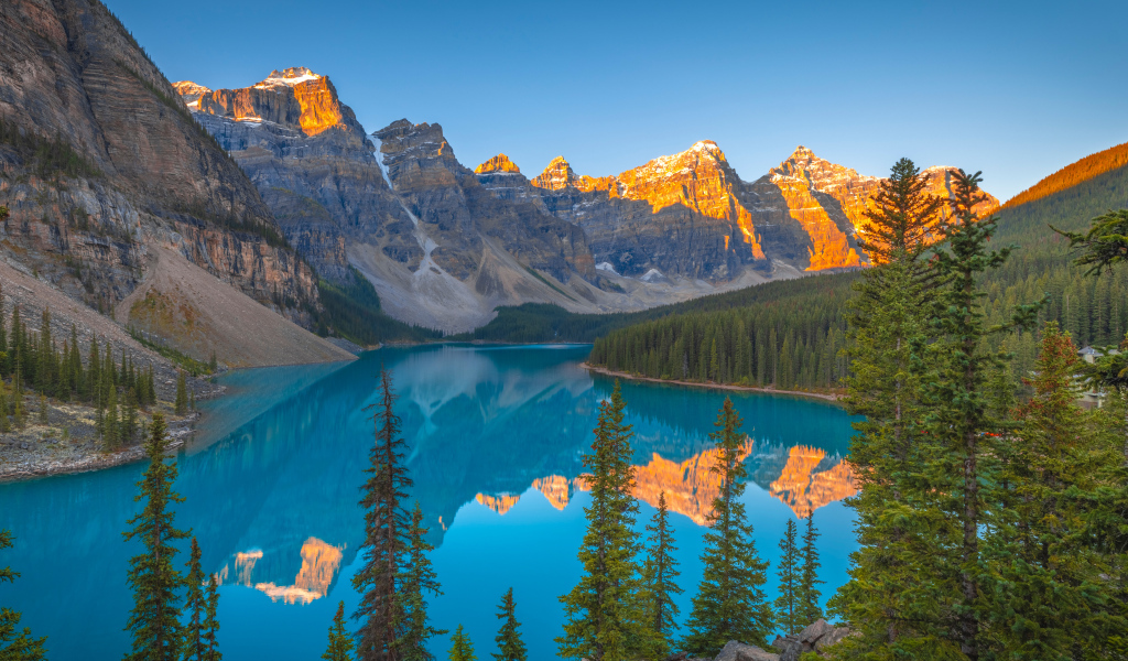 Солнце над вершинами гор у голубого озера