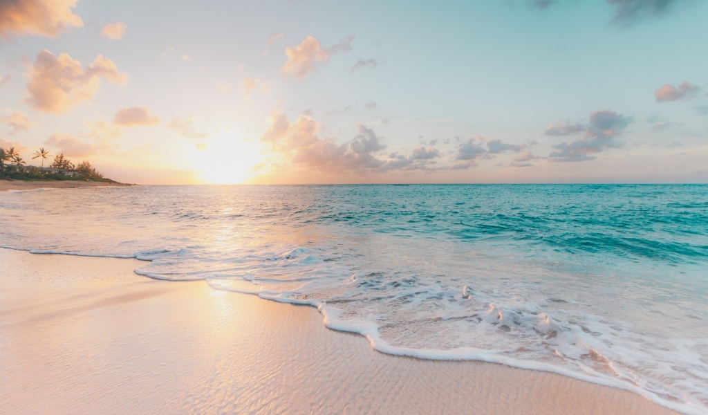 Красивая вода океана на песке в лучах закатного солнца