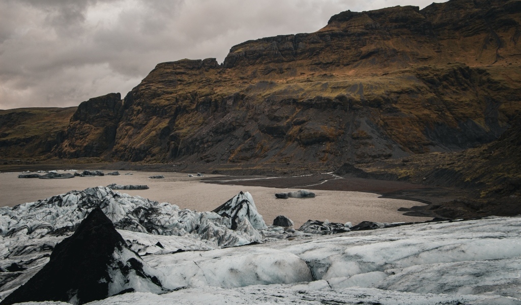 Холодный грязный снег на берегу моря у гор 