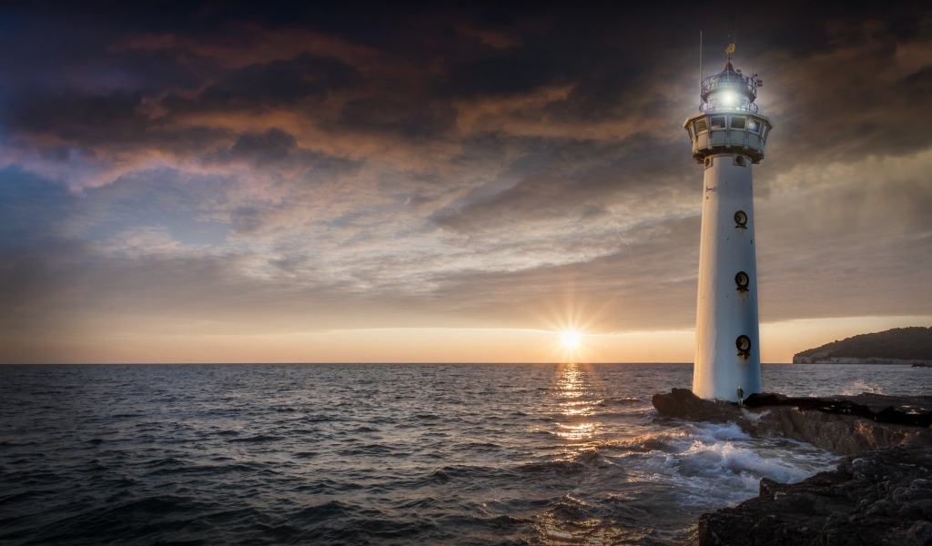 Высокий маяк на берегу моря на закате