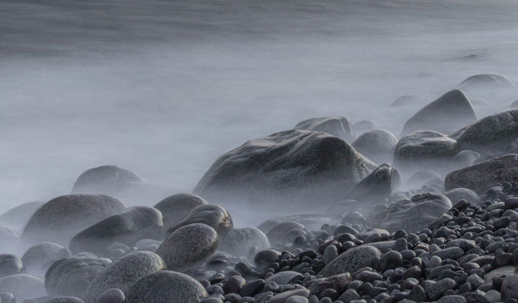 Большие черные камни на берегу моря в тумане