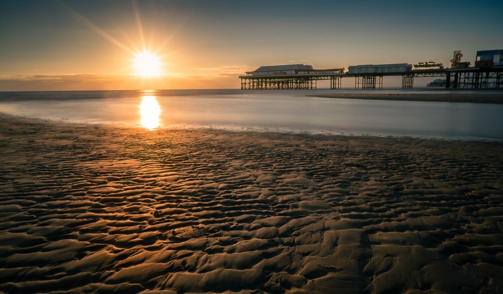 Мокрый песок на берегу моря на закате