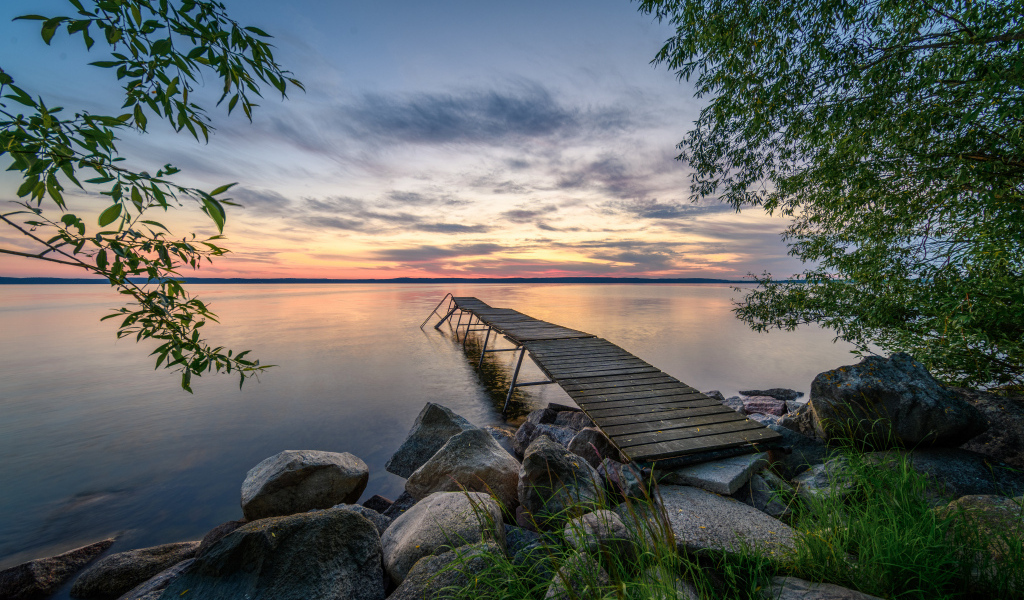 Старый деревянный пирс у озера на закате