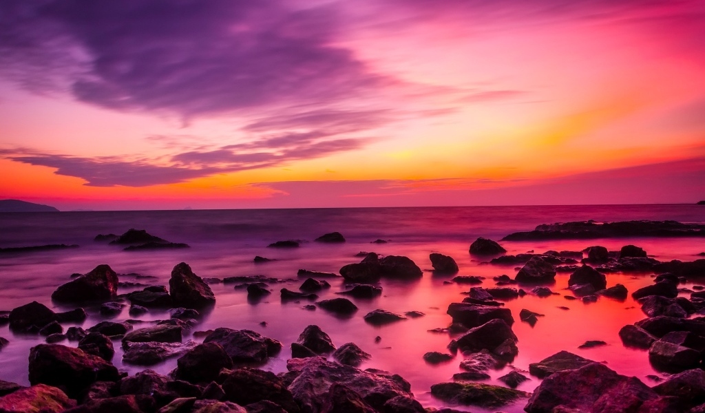 Розовый закат на каменном берегу моря