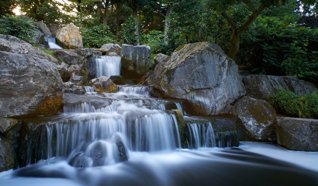 Водопад стекает по большим холодным камням в лесу