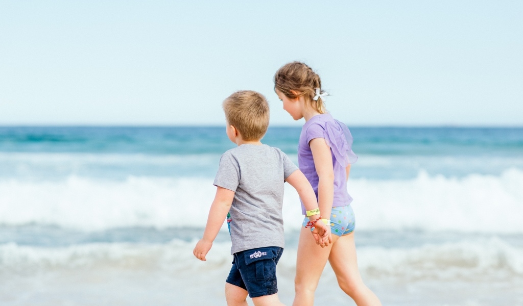 Мальчик и девочка идут по песку у моря