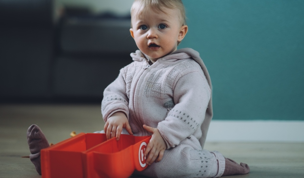 Маленький мальчик в теплом костюме сидит на полу