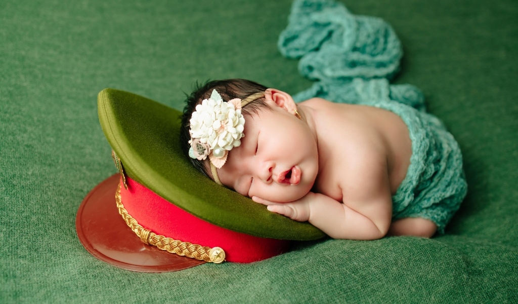 Маленький ребенок спит на военной фуражке