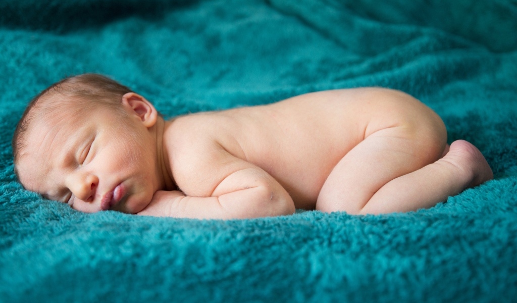 Грудной ребенок спит на синем пледе