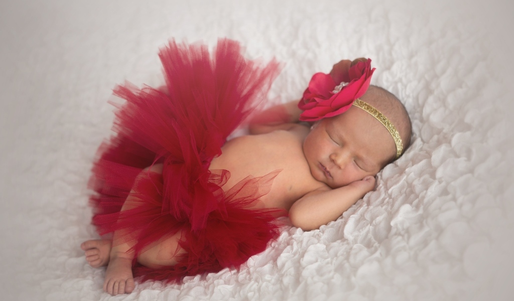 Красивая пышная красная юбка и бант на спящей малышке