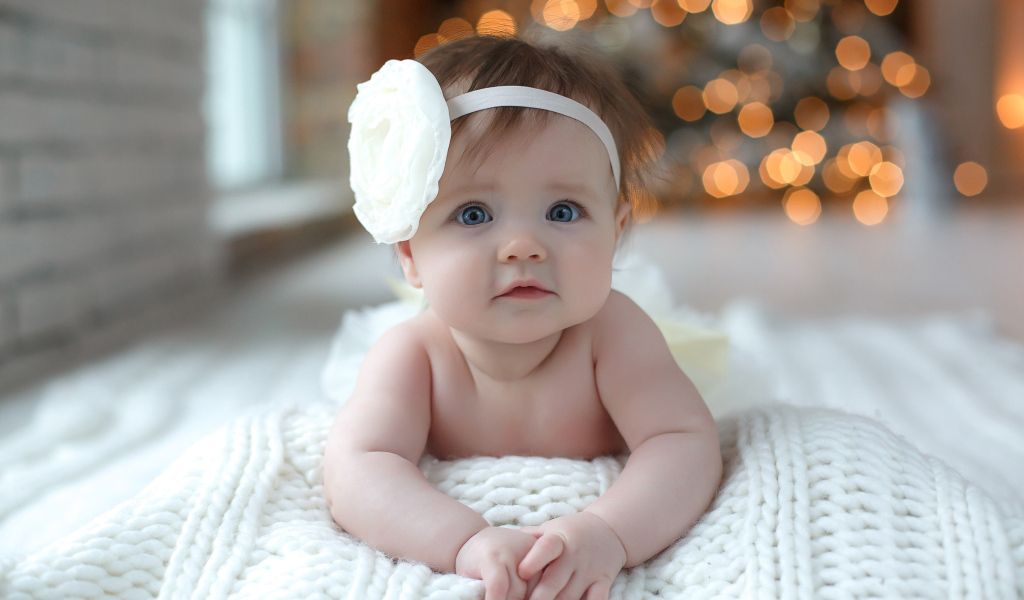 Красивая маленькая девочка с белым цветком на голове