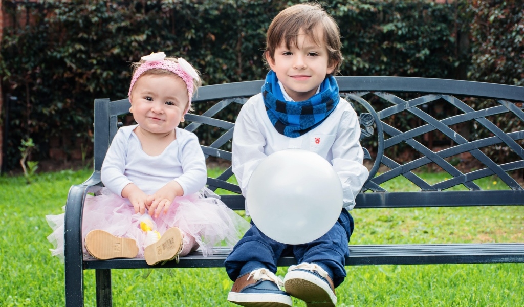 Мальчик и девочка сидят на лавке в парке