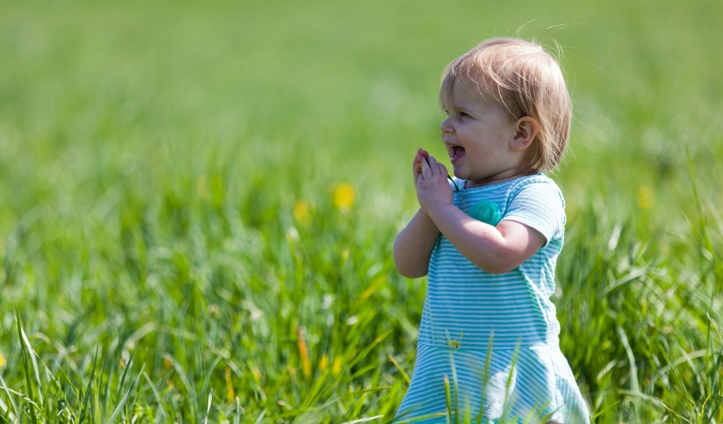 Веселая девочка на поле с зеленой травой
