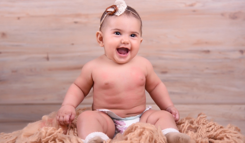 Милый улыбающийся ребенок на фоне деревянной стены