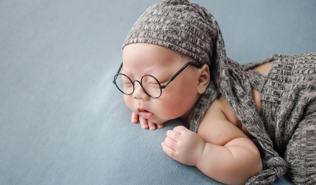 Забавный малыш в очках одет в серый костюм