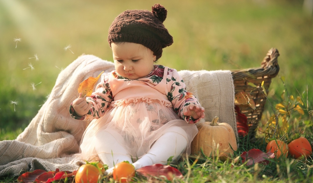 Смешная маленькая девочка сидит на траве с тыквой