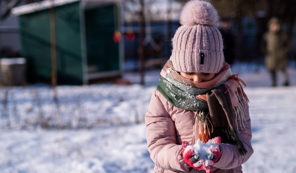 Девочка держит снег в руках зимой