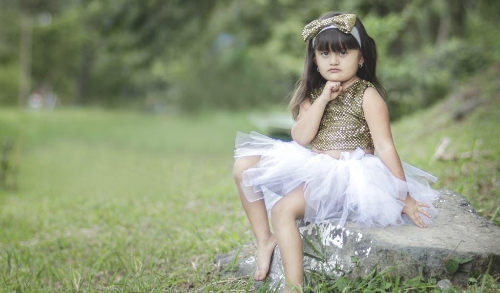 Девочка в красивом платье сидит на камне