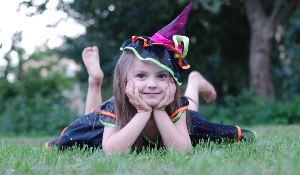 Девочка в костюме лежит на зеленой траве