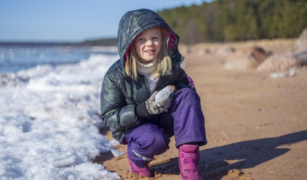 Девочка сидит у замерзшего озера 