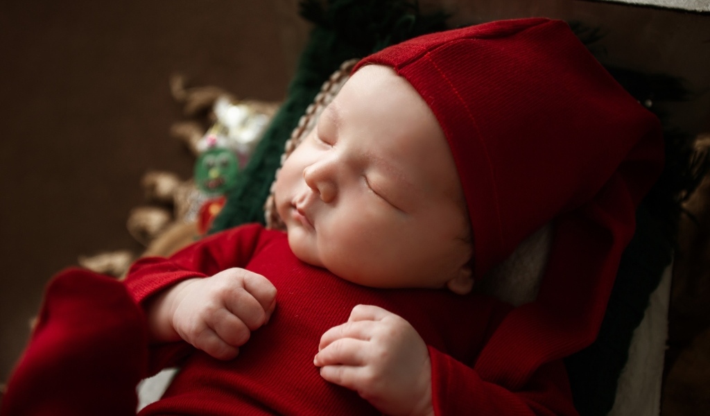 Маленький ребенок спит в красном костюме