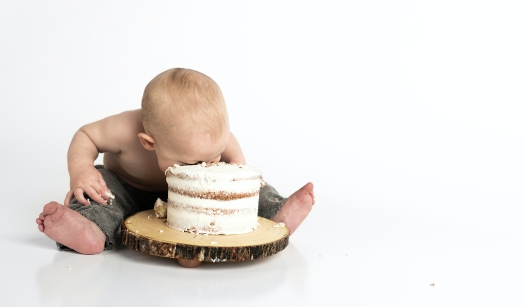 Маленький мальчик ест праздничный торт на белом фоне