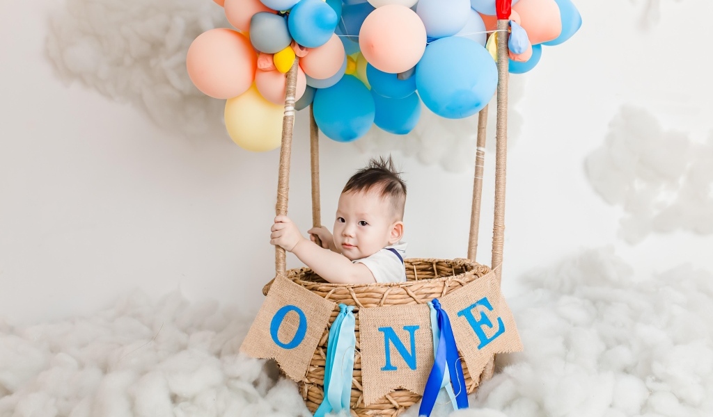 Маленький мальчик в корзине с воздушными шарами