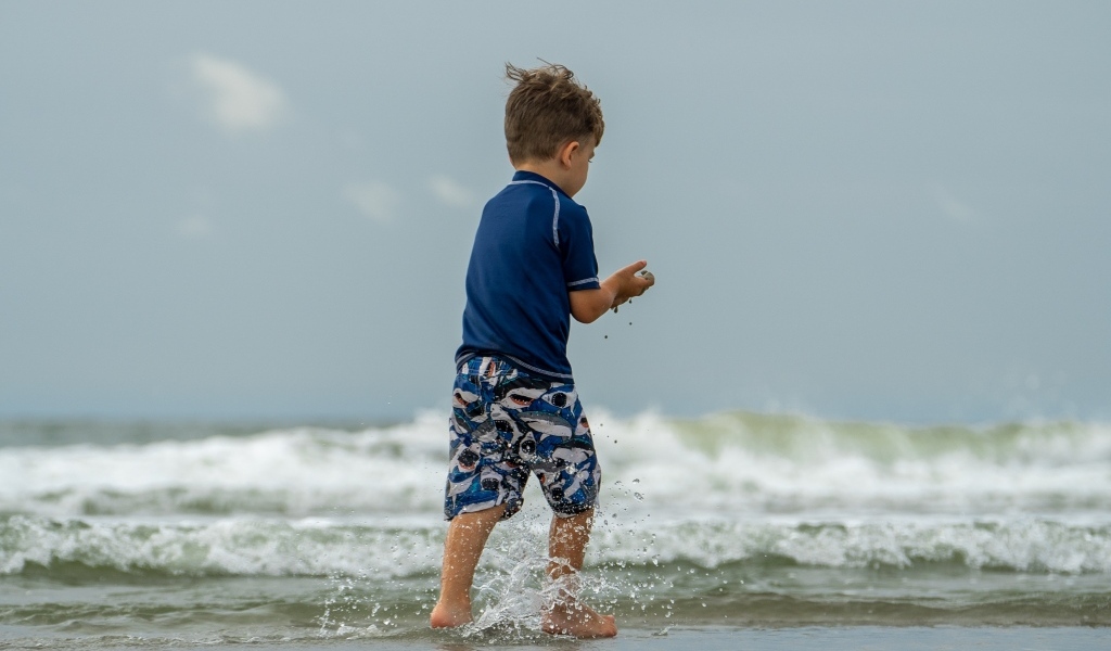 Маленький мальчик гуляет по морскому берегу