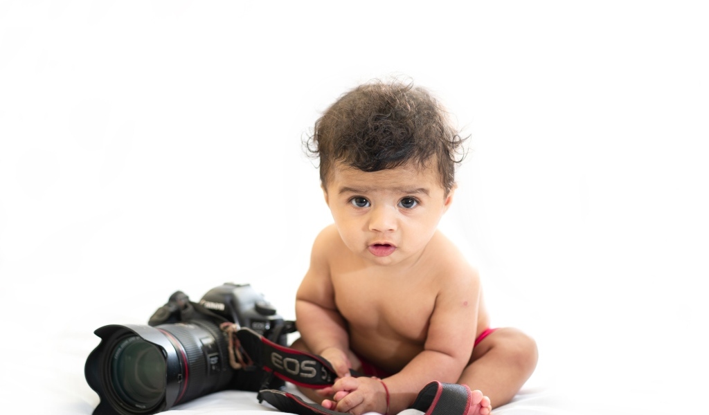 Маленький мальчик с фотоаппаратом на белом фоне
