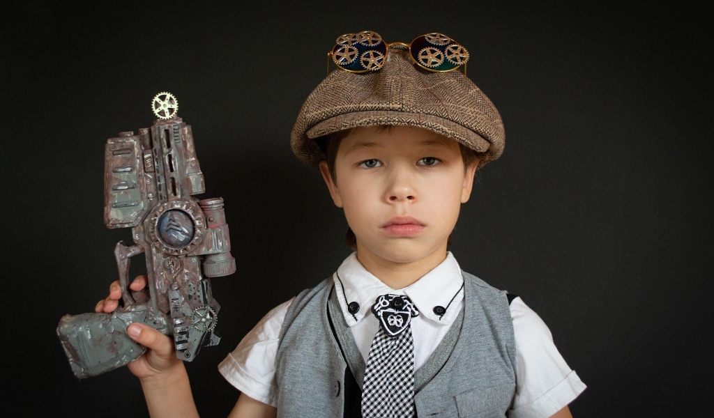 Маленький мальчик с игрушечным пистолетом на черном фоне