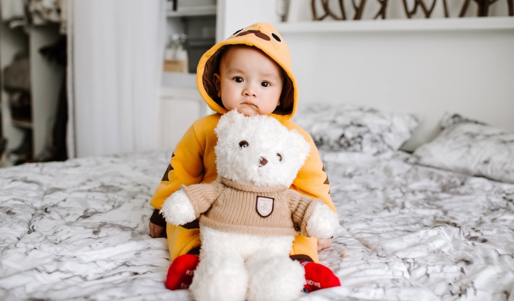 Маленький ребенок с игрушкой на кровати 