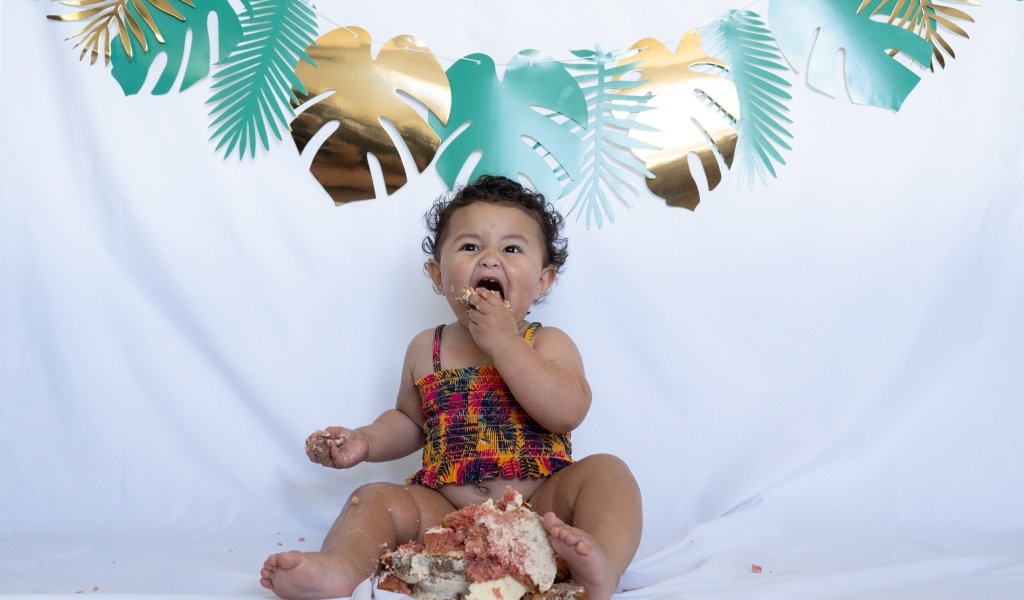 Маленькая девочка ест торт на белом фоне