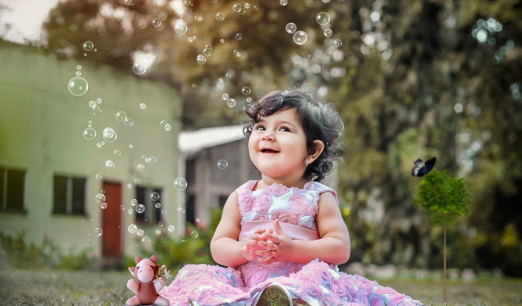 Маленькая девочка радуется мыльным пузырям