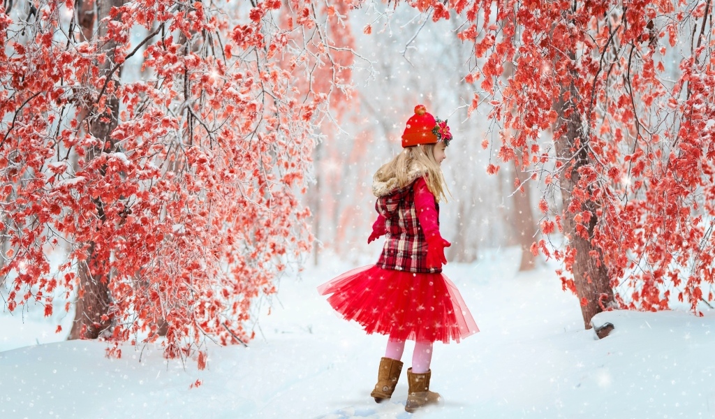 Маленькая девочка в красном платье в зимнем лесу